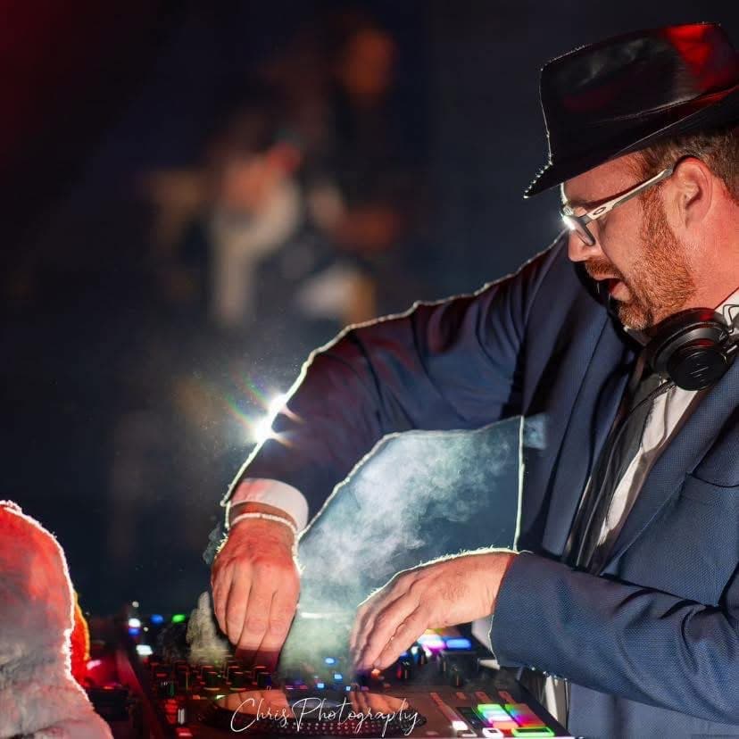 Gros plan de Julien Bonhomme aux platines, les mains sur les commandes, dans une fumée traversée de lumière rouge.