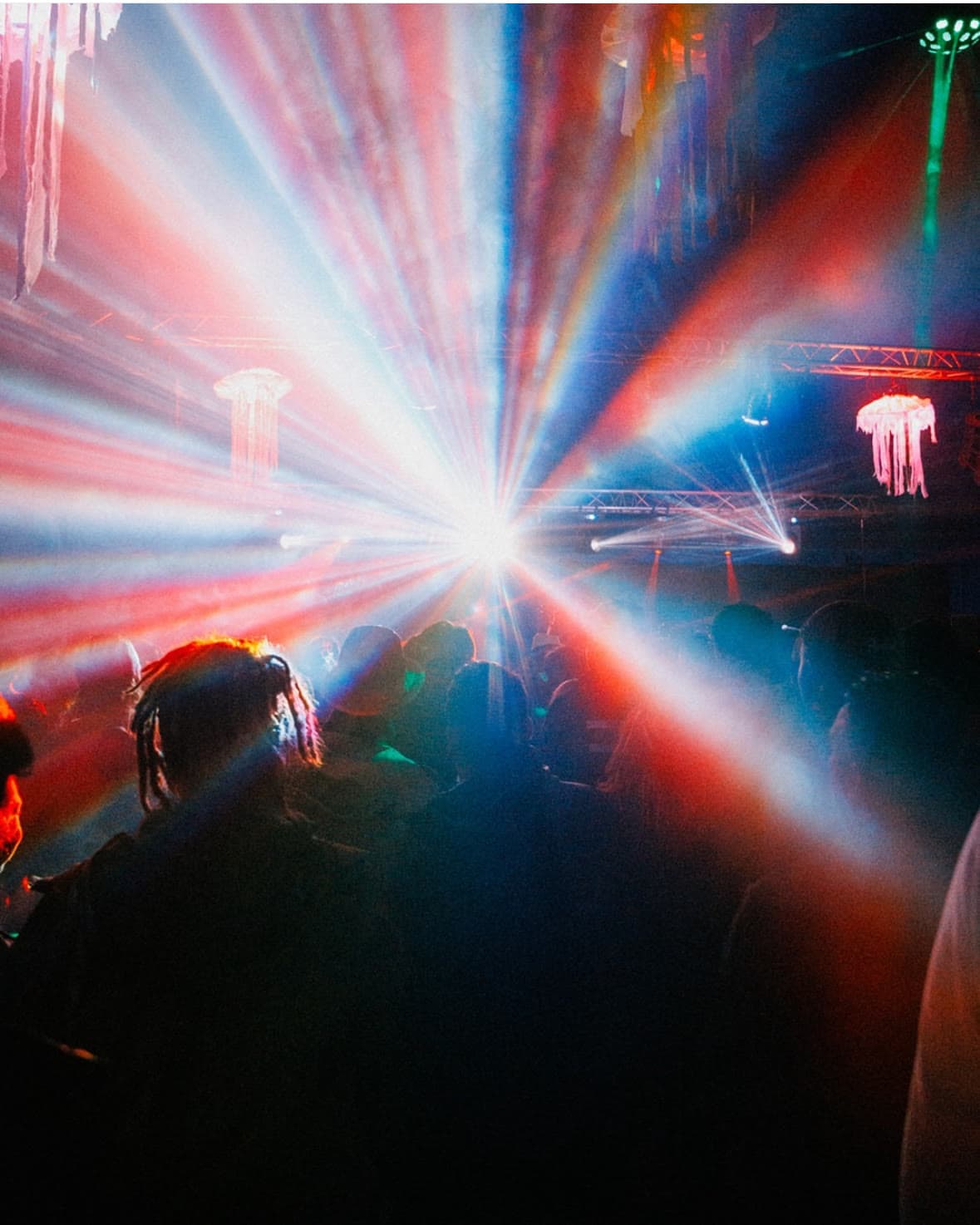Gerbe de lasers rouges et bleus jaillissant au-dessus d'un public dense.